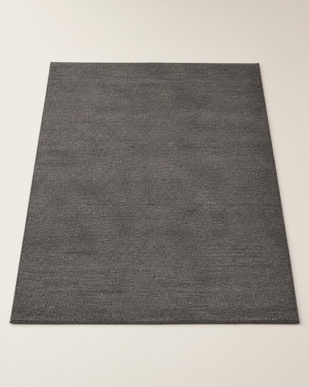 Kahat Wool Blend Rug — charcoal wool blend rug with a low, dense flat weave, 200×290 cm, styled in a minimalist cream interior